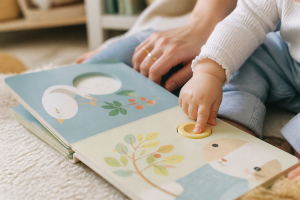 Main de bébé appuyant sur la puce sonore d'un livre cartonné